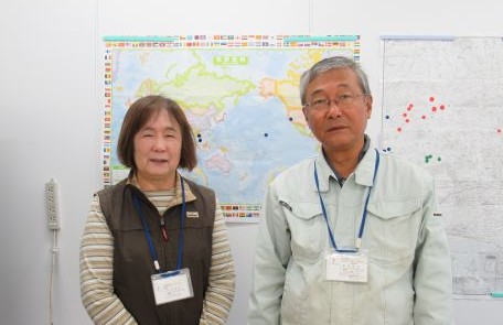 世界地図の前の田中さん夫妻