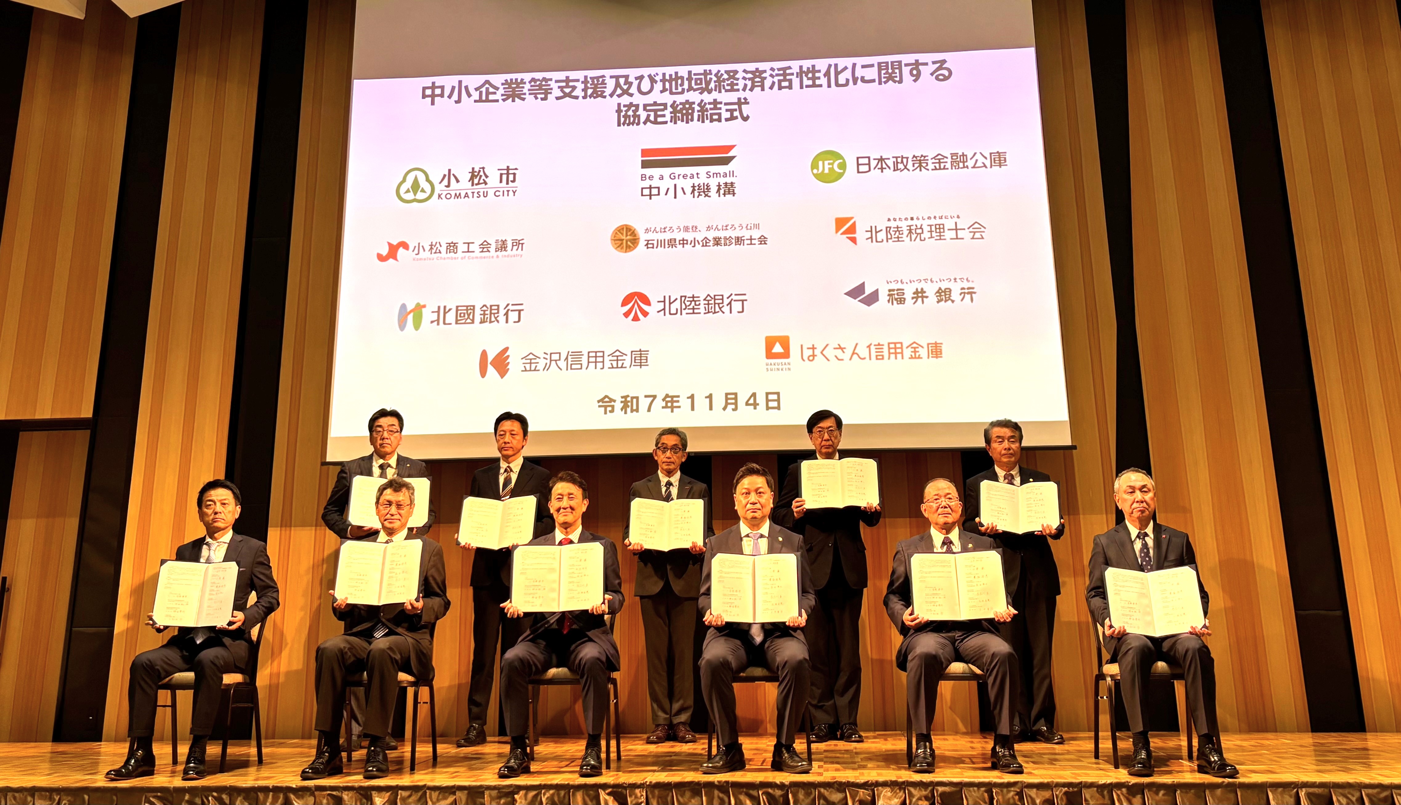 署名された覚書を掲げ記念撮影する様子